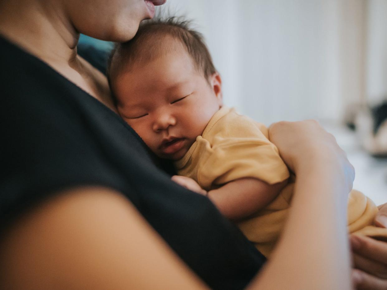 A newborn baby lies on their mother's chest.