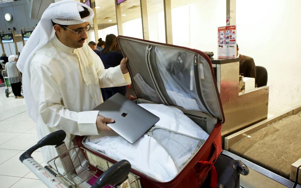  Kuwaiti social media activist Thamer al-Dakheel Bourashed putting his laptop inside his suitcase at Kuwait International Airport in Kuwait City before boarding a flight to the United States - Credit: AFP