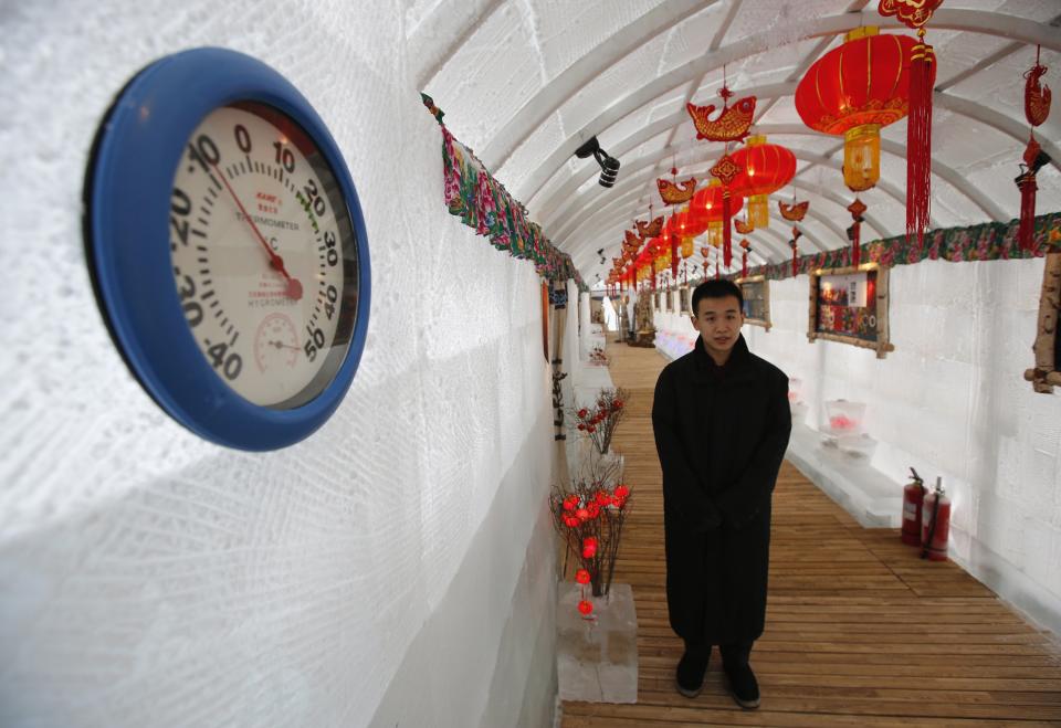 A waiter stands next to thermometer indicating -10 degree reading during photo opportunity at Ice Palace in Shangri-La Hotel in Harbin