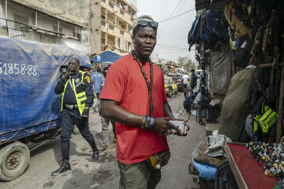 Gueva Ba sells used cell phones in Dakar's Colobane market Thursday, Feb. 1, 2024. Ba, who tried to reach Europe via Morocco eleven times, flew legally to Nicaragua and made the rest of the journey illegally by land to Mexico's northern border, before being repatriated from the United States to Senegal in September 2023. (AP Photo/Sylvain Cherkaoui)