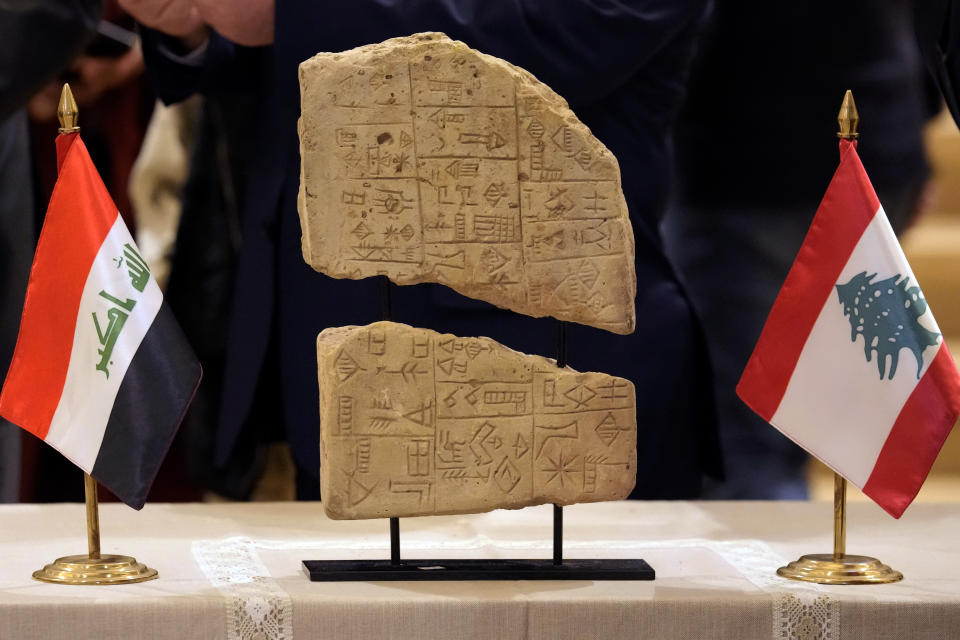 An Iraqi clay tablet is displayed between a Lebanese flag, right, and an Iraqi flag during a ceremony held at the National Museum of Beirut, before 337 artifacts were handed over by Lebanese Minister of Culture Mohammed Murtada to Iraq's ambassador to Lebanon, in Beirut, Lebanon, Sunday, Feb. 6, 2022. Until they were handed over, the artifacts had been kept at the private Nabu Museum in north Lebanon. (AP Photo/Bilal Hussein)