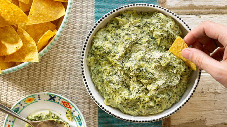 Bowl of green dip with hand