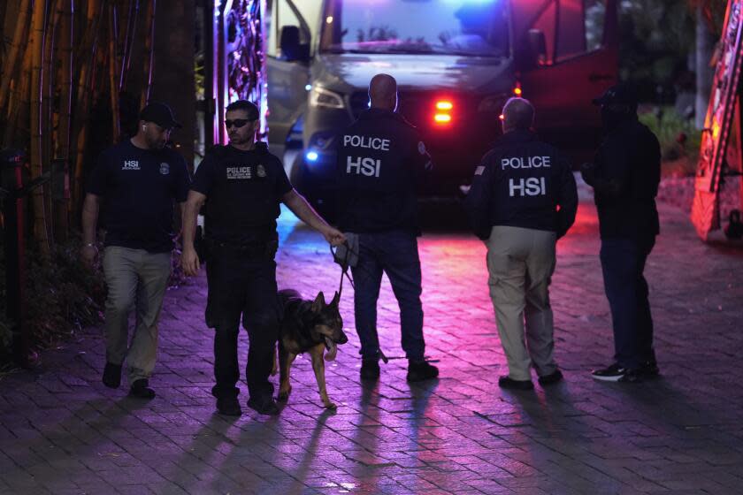 A law enforcement officer leads out a canine as federal agents stand at the entrance to a property belonging to rapper Sean "Diddy" Combs, Monday, March 25, 2024, on Star Island in Miami Beach, Fla. Two properties belonging to Combs in Los Angeles and Miami were searched Monday by federal Homeland Security Investigations agents and other law enforcement as part of an ongoing sex trafficking investigation by federal authorities in New York, two law enforcement officials told The Associated Press. (AP Photo/Rebecca Blackwell)