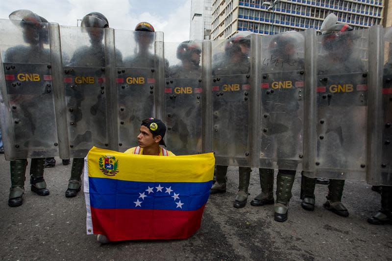 Un hombre sostiene una bandera venezolana frente a miembros de la Guardia Nacional Bolivariana (GNB) en la protesta de este miércoles 18 de mayo de 2016 (EFE/MIGUEL GUTIÉRREZ)