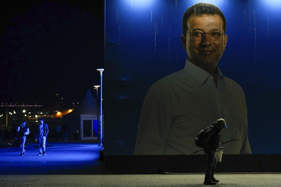 A man walks past a giant campaign poster of Istanbul Mayor and Republican People's Party, or CHP, candidate for Istanbul Ekrem Imamoglu, in Istanbul, Turkey, Wednesday, March 20, 2024. With local elections across Turkey days away, legal experts are coaching thousands of volunteer election monitors on the rules they'll need to watch for fraud and ensure a fair vote. (AP Photo/Emrah Gurel)