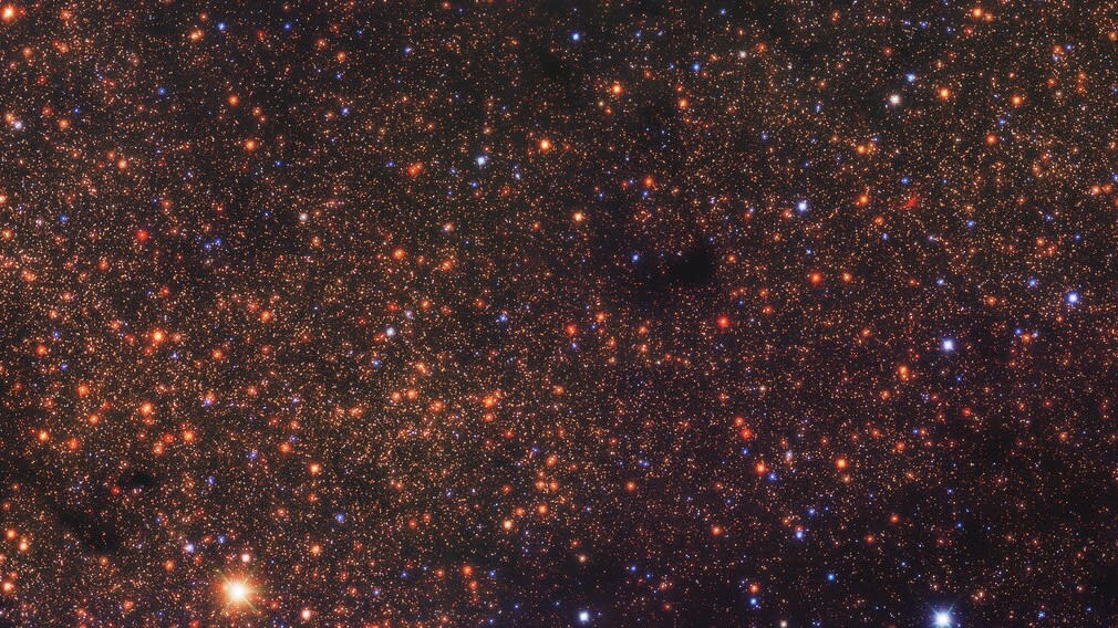  Deep-space photo showing thousands of reddish-orange dots, each of which is a distant star. 