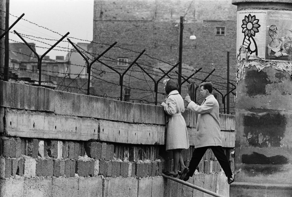 21/4/1962- A young woman, accompanied by her boyfriend, stands precariously near the top of the Berlin Wall to talk to her mother on the East Berlin side. Picture- Corbis Images