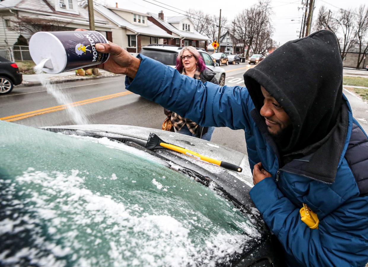 Christie Hinkle brings George Lindsey Jr some salt to help to melt the ice on his windshield on Tuesday morning, January 31, 2023, in the Schnitzelberg-Germantown area