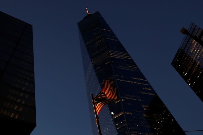 The One World Trade Center building is illuminated in red to honor the lives lost to the coronavirus disease (COVID-19) as the U.S. flag blows