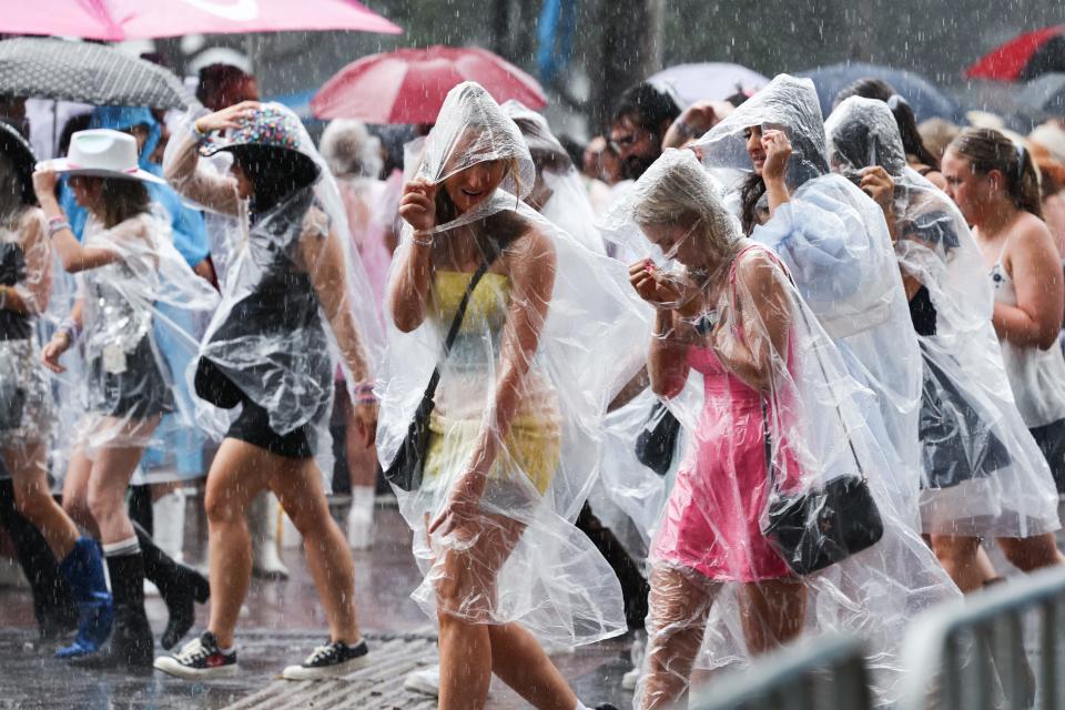 Fans of US singer Taylor Swift, also known as a Swifties, shelter from the rain as they arrive for Swift's concert in Sydney on February 23, 2024.