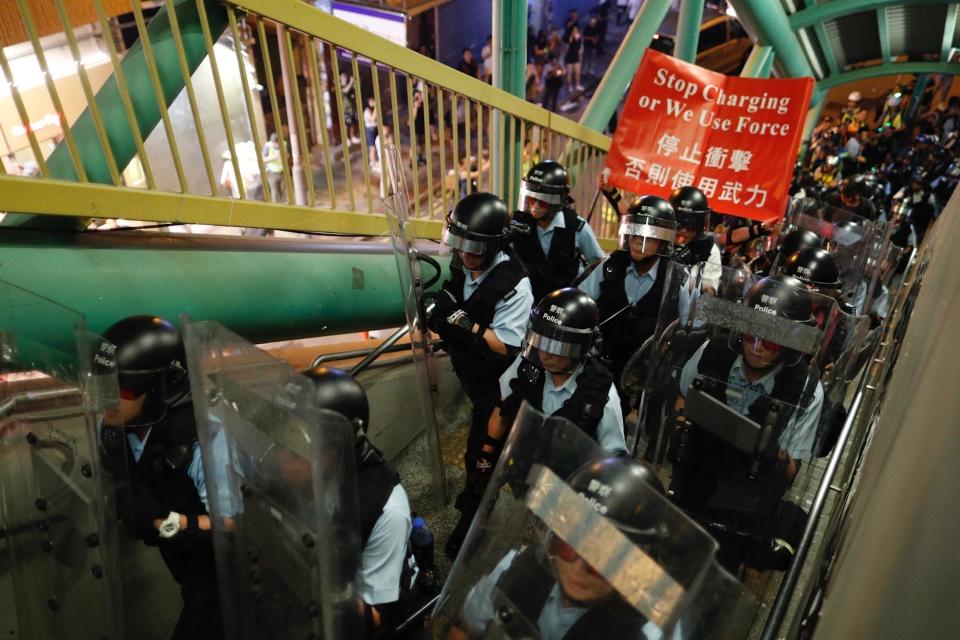 Police move out from the Shum Shui Po police station to confront protesters in Hong Kong on Wednesday, Aug. 14, 2019. German Chancellor Angela Merkel is calling for a peaceful solution to the unrest in Hong Kong amid fears China could use force to quell pro-democracy protests.(AP Photo/Vincent Yu)