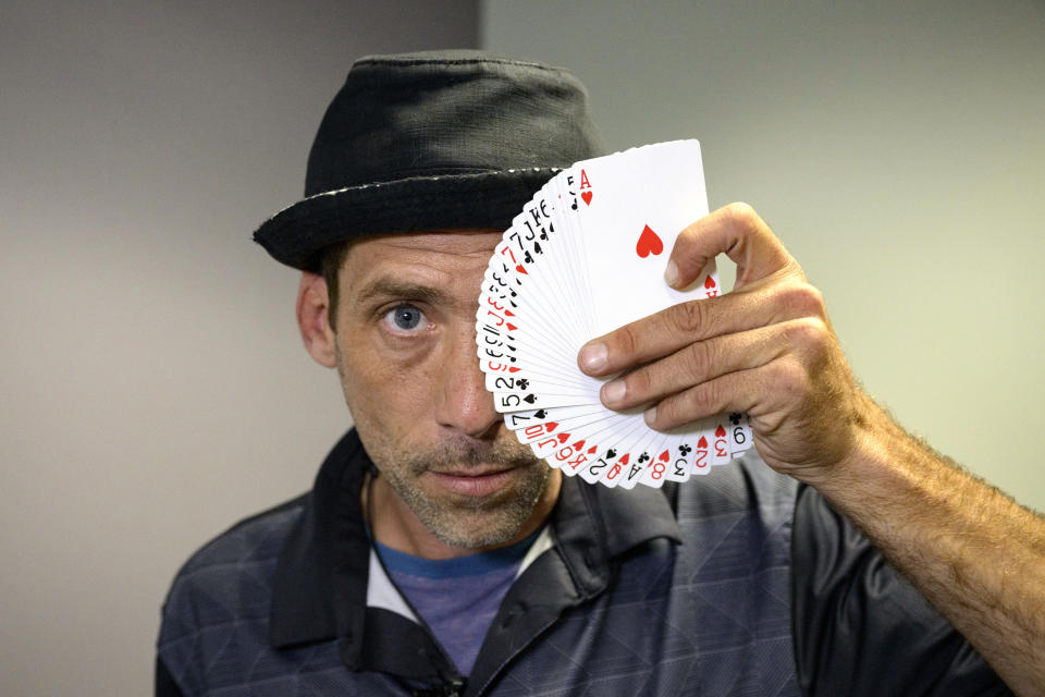 Paul Carpenter, a New Orleans magician, performs card tricks during an interview in New Orleans, Friday, Feb. 23, 2024. Carpenter says he was hired in January by Steve Kramer, who has worked on ballot access for Democratic presidential candidate Dean Phillips, to use AI software to imitate President Joe Biden's voice to convince New Hampshire Democrat voters not to vote in the state's presidential primary. (AP Photo/Matthew Hinton)