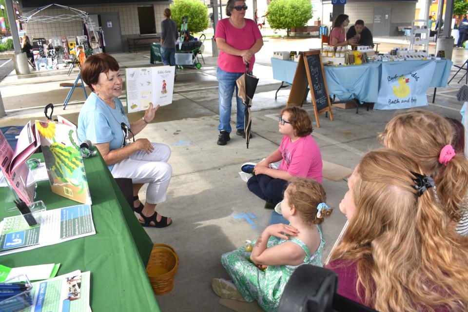 Margie Dennis, left, a youth services clerk with the Adrian District Library, conducted two storytime programs Saturday morning and afternoon during the grand opening of the new Adrian City Market at the Pavilion in downtown Adrian. Dennis read the children's story "Eddie's Garden and How to Make Things Grow" by Sarah Garland to groups of listeners during the market's opening day.