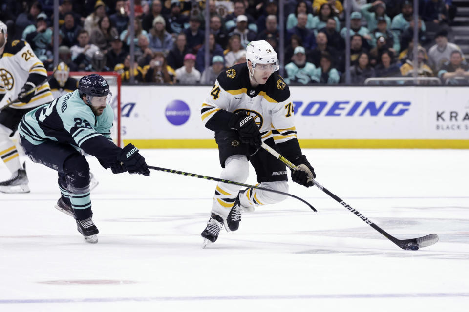 Boston Bruins left wing Jake DeBrusk (74) skates with the puck as Seattle Kraken right wing Oliver Bjorkstrand (22) defends during the third period of an NHL hockey game Thursday, Feb. 23, 2023, in Seattle. The Bruins won 6-5. (AP Photo/John Froschauer)