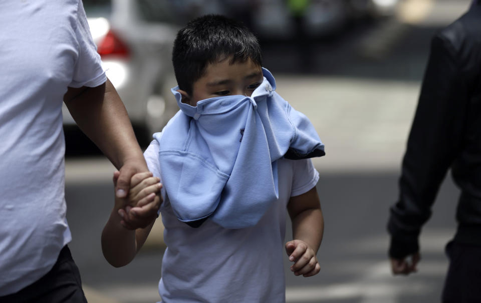 <p>A boy with his face covered due to a gas leak holds aman’s hand as people gather in Reforma Avenue after an earthquake in Mexico City, Tuesday Sept. 19, 2017. A powerful earthquake jolted central Mexico on Tuesday, causing buildings to sway sickeningly in the capital on the anniversary of a 1985 quake that did major damage.(AP Photo/Marco Ugarte) </p>