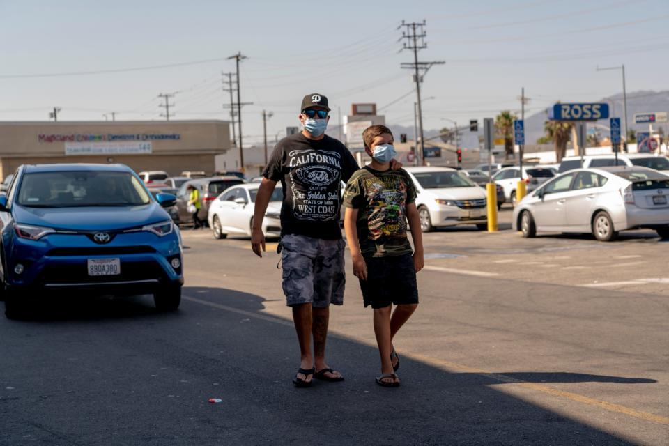 Joel Reynozo, left, walks with his son, Jared, 11, after leaving a Target store in Pacoima last week. Reynozo, who is unvaccinated, says he would pull his son out of Los Angeles Unified if the district requires students to be vaccinated.