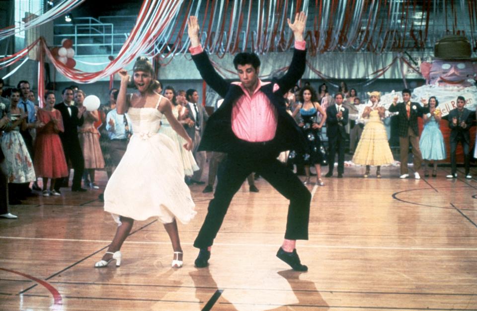 1978 : La chanteuse et actrice australienne Olivia Newton-John et l'acteur américain John Travolta dansent dans la salle de sport bondée d'un lycée dans une image tirée du film 