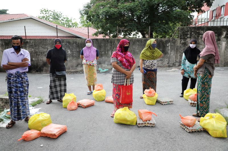 FILE PHOTO: Rohingya refugees wearing protective masks keep a social distance while waiting to receive goods from volunteers, during the movement control order due to the outbreak of the coronavirus disease (COVID-19), in Kuala Lumpur