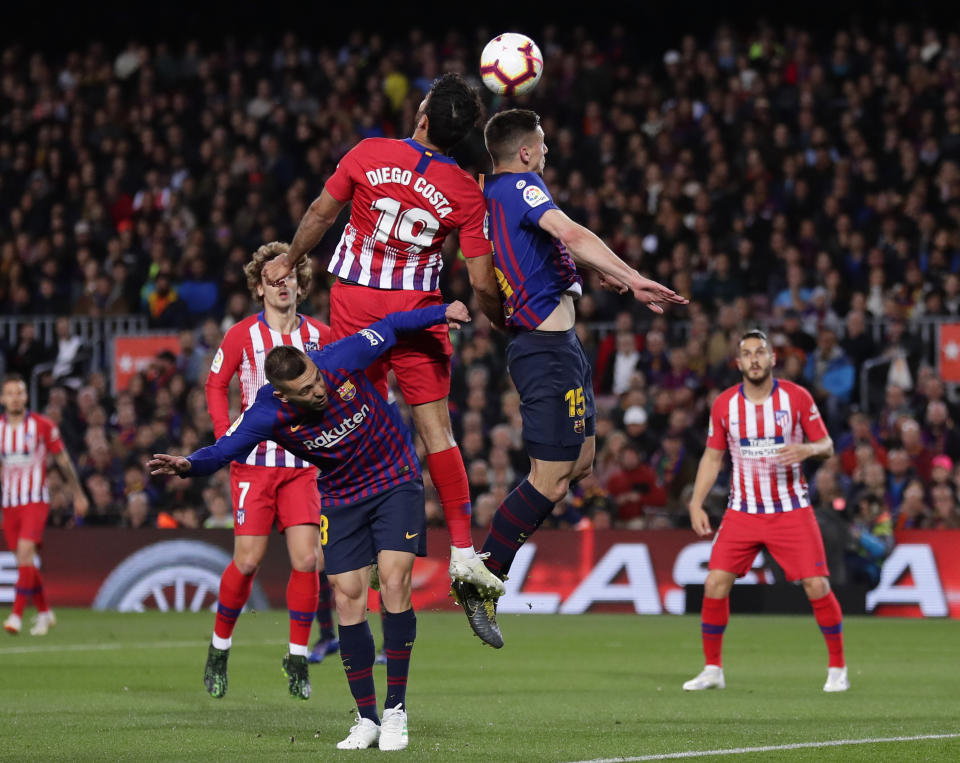 Barcelona midfielder Arthur ducks as Atletico forward Diego Costa, center left, and Barcelona defender Clement Lenglet, center right, jump to head the ball during a Spanish La Liga soccer match between FC Barcelona and Atletico Madrid at the Camp Nou stadium in Barcelona, Spain, Saturday April 6, 2019. (AP Photo/Manu Fernandez)