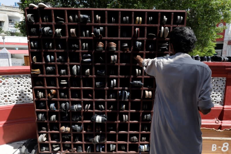 A man keeps his pair of sandals with others in a rack as he attends Friday prayer amid an outbreak of the coronavirus disease (COVID-19), at a mosque in Karachi