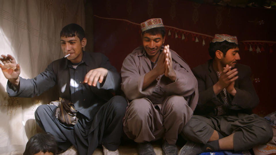 Three men sitting side by side and clapping