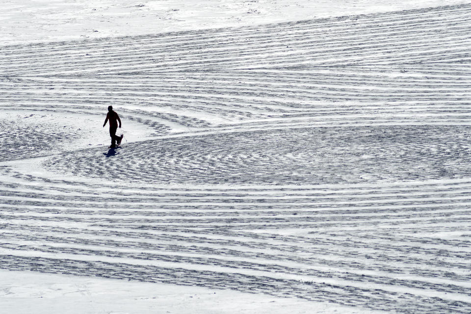 In this photo taken Jan. 7, 2020, British artist Simon Beck uses snowshoes to create a massive geometrical design on a reservoir near Silverthorne, Colo. The 61-year-old has completed about 330 snow drawings and 120 in sand since he started the art form outside his winter home at a French ski resort in 2004. He says he hopes his drawings bring awareness to the beauty of the environment. (AP Photo/Thomas Peipert)