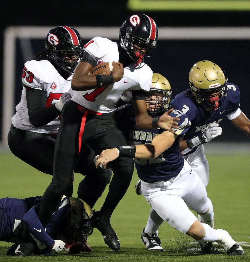 Hoban linebacker Eli Lee, right center, and defensive back Ayden Boykin, bottom, work to bring down Glenville running back D'Shawntae Jones during the first half of a high school football game, Friday, Oct. 6, 2023, in Akron, Ohio.