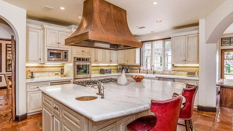 The chef's kitchen has a marble island bench with breakfast bar.