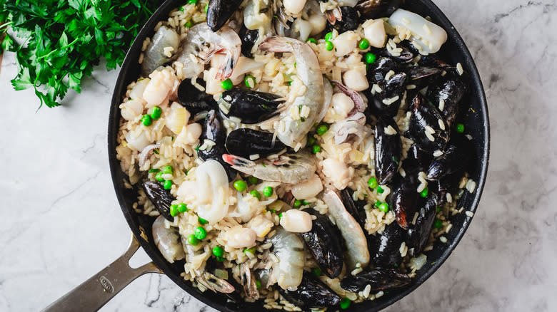 Seafood added to pan of risotto