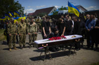 Iuliia Loseva, center, and her sons Hryhorii and Denys stand over the coffin of their husband and father Volodymyr Losev, 38, during his funeral in Zorya Truda, Odesa region, Ukraine, Monday, May 16, 2022. Volodymyr Losev, a Ukrainian volunteer soldier, was killed May 7 when the military vehicle he was driving ran over a mine in eastern Ukraine. (AP Photo/Francisco Seco)