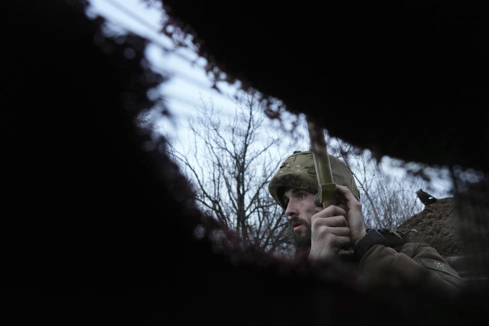 A Ukrainian service member listens to artillery shots standing in a trench on a position at the line of separation between Ukraine-held territory and rebel-held territory near Zolote, Ukraine, late Saturday, Feb. 19, 2022. Ukrainian President Volodymyr Zelenskyy, facing a sharp spike in violence in and around territory held by Russia-backed rebels and increasingly dire warnings that Russia plans to invade, has called for Russian President Vladimir Putin to meet him and seek a resolution to the crisis. (AP Photo/Evgeniy Maloletka)