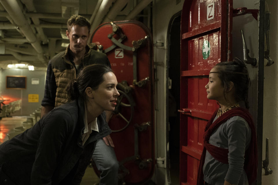 This image released by Warner Bros. Entertainment shows Alexander Skarsgard, background, Rebecca Hall, foreground left, and Kaylee Hottle in a scene from "Godzilla vs. Kong." (Chuck Zlotnick/Warner Bros. Entertainment via AP)