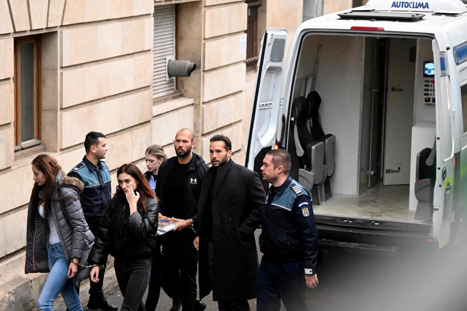Police escort Andrew Tate, third from right handcuffed to his brother, Tristan, and two unidentified Romanian women into a courthouse in Bucharest on Jan. 10, 2023. Tate was detained last month on charges of rape, human trafficking and running an organized crime ring.