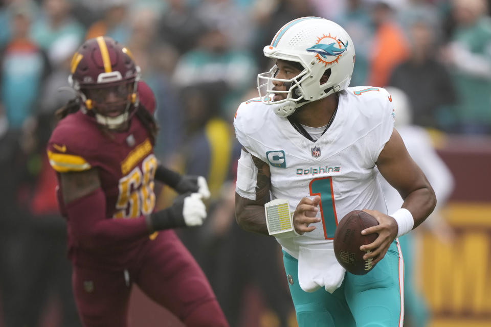 Miami Dolphins quarterback Tua Tagovailoa (1) rolls out in front of Washington Commanders defensive end Andre Jones Jr. during the first half of an NFL football game Sunday, Dec. 3, 2023, in Landover, Md. (AP Photo/Mark Schiefelbein)