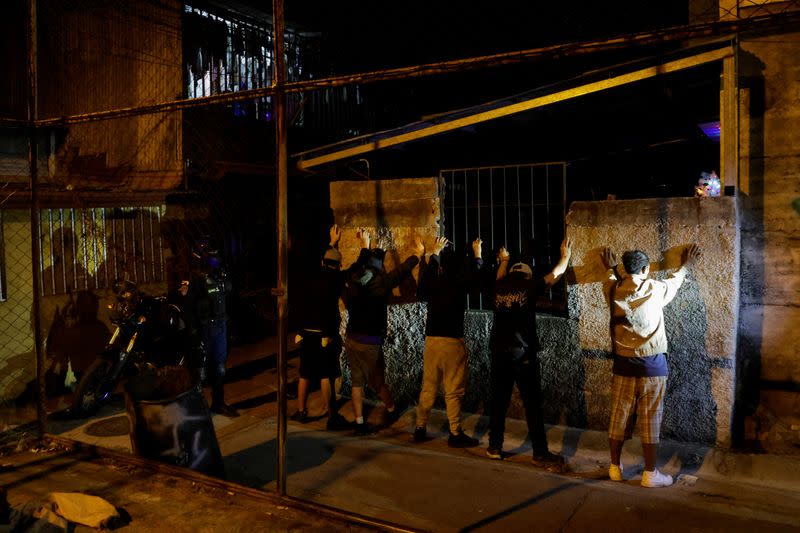 A police officer stands next to men briefly detained to frisk them for drugs and weapons during the "Costa Rica Segura Plus" operation, in San Jose