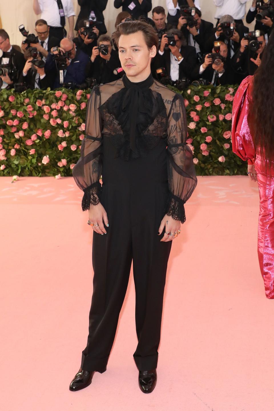 Harry Styles at the 2019 Met Gala in high-waisted black trousers with a puffy, sheer top.