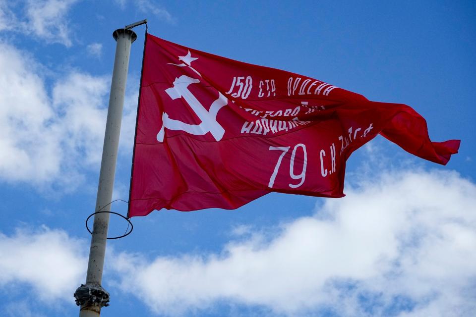 A red flag, a replica of the Victory banner flutters in the wind over the central square of Melitopol, in a territory under Russian military control, southeastern Ukraine, May 1, 2022.