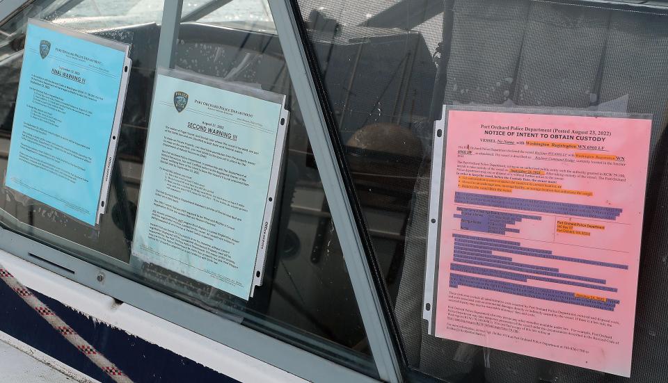 Two warnings and a final notice of custody from the Port Orchard Police Department adorn the window of a derelict vessel at DeKalb Pier in Port Orchard on Monday.