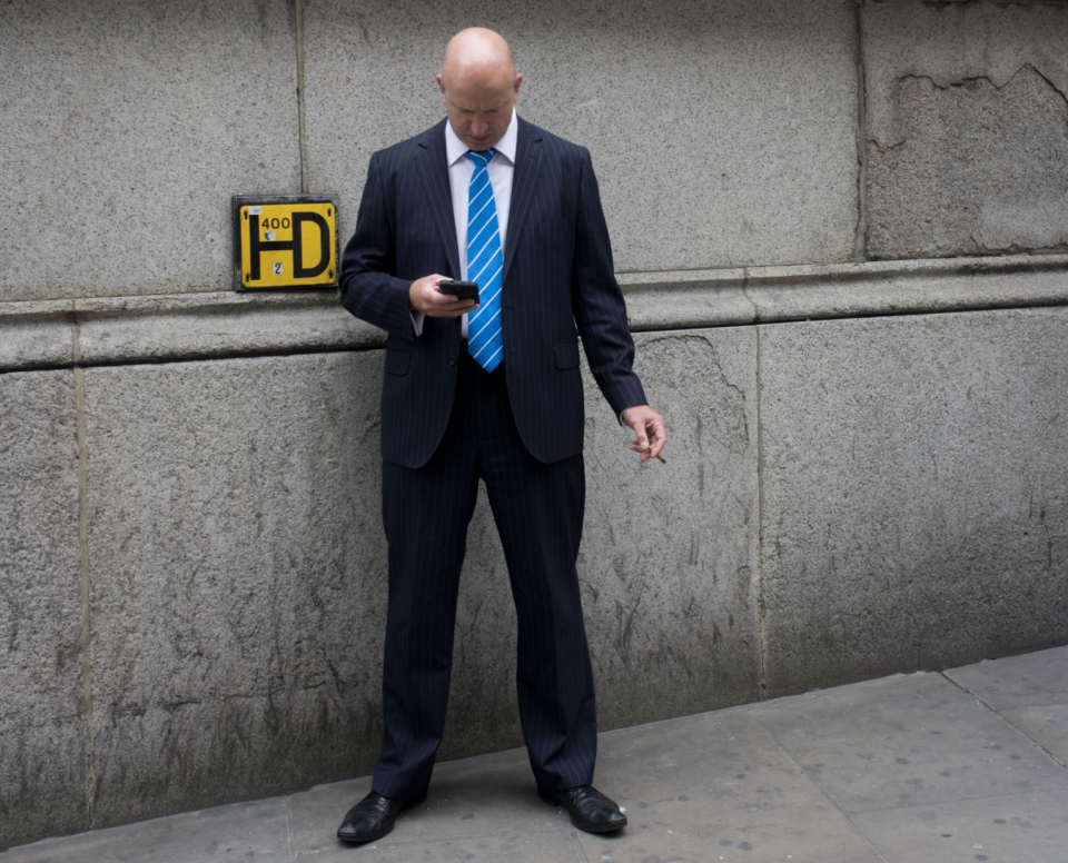 Een man checkt zijn telefoon buiten de Royal Exchange in Londen. (Foto door In Pictures Ltd./Corbis via Getty Images)