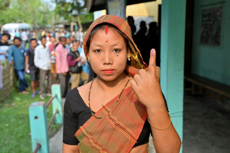 A woman shows her inked finger after casting her ballot in India’s general election at a polling station in Nagaon in the northeastern state of Assam on 19 April 2024 (AFP via Getty Images)