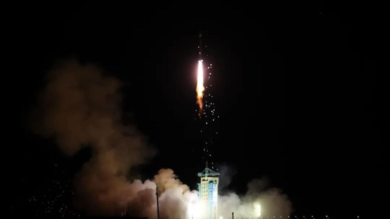  the orange exhaust plume from a launching rocket lights up a black night sky 