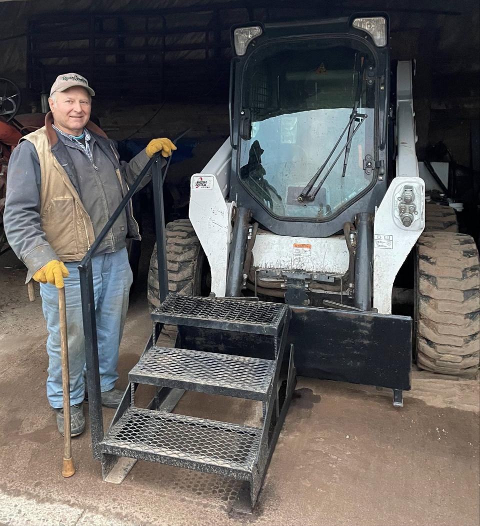 Livestock farmer Scott Cebery uses steps and a handrail provided by Wisconsin's Division of Vocational Rehabilitation to safely board his skid-steer.