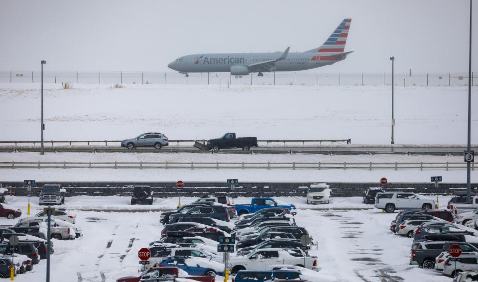 A jet passes snow-covered cars parked at Denver International Airport on Nov. 26, 2019, in Denver. Flights were delayed and rescheduled due to a winter storm that dropped nearly a foot of snow in the city. 