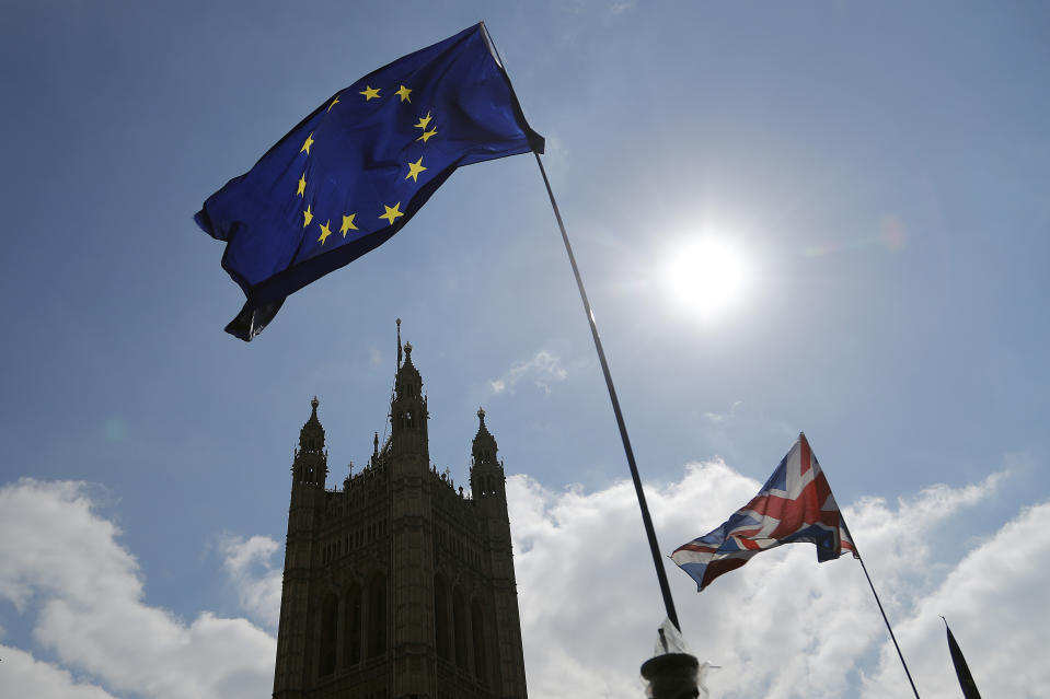 FILE - In this Thursday, April 11, 2019 file photo, protestor flags fly opposite the Houses of Parliament in London. The British economy is likely to weaken as firms stop ease up on Brexit preparations now that Britain’s departure from the European Union has been delayed by months, the Bank of England said Thursday, May 2, 2019. (AP Photo/Frank Augstein, File)