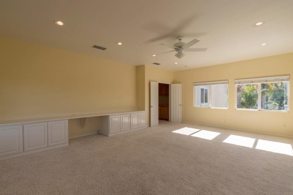 An empty yellow room with cream carpets.