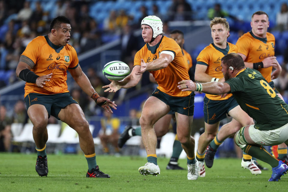 Australia's Michael Hooper, center, unloads the ball to teammate Allan Alaalatoa as South Africa's Duane Vermeulen, right, comes in to tackle during their Rugby Championship match on Sunday, Sept. 12, 2021, Gold Coast, Australia. (AP Photo/Tertius Pickard)