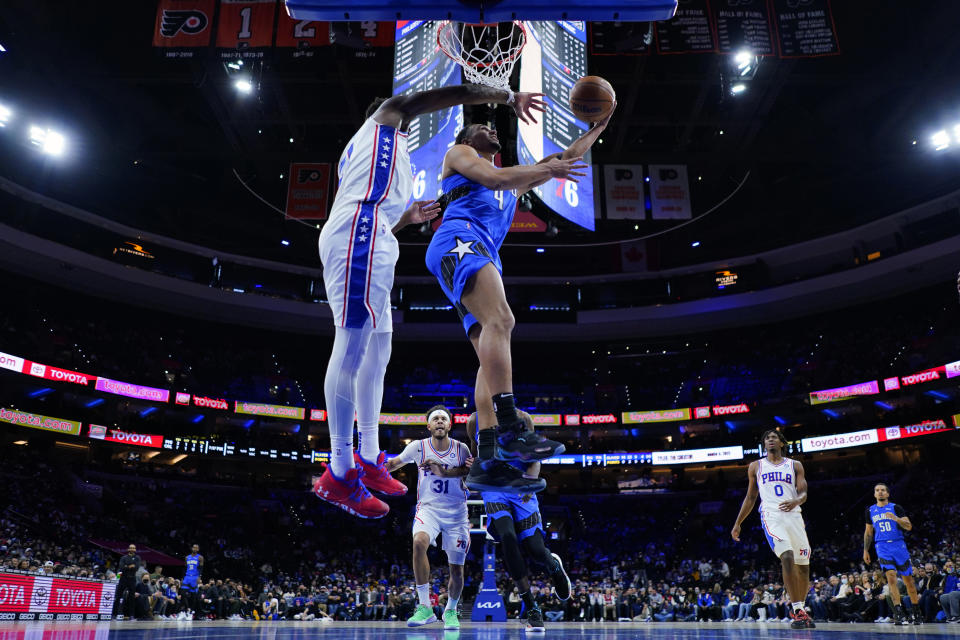 Orlando Magic's Jalen Suggs, right, goes up for a shot against Philadelphia 76ers' Joel Embiid during the first half of an NBA basketball game, Wednesday, Jan. 19, 2022, in Philadelphia. (AP Photo/Matt Slocum)