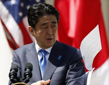 Japanese Prime Minister Shinzo Abe's papers go flying as he addresses a joint news conference with U.S. President Barack Obama in the Rose Garden of the White House in Washington, April 28, 2015. REUTERS/Kevin Lamarque