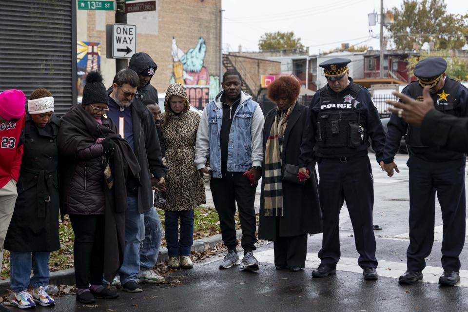 Community members, city officials and Chicago police join hands in prayer Sunday, Oct. 29, 2023, at the scene of a shooting that wounded 15 people after a shooter fired shots into a crowd at a Halloween party in Chicago. Shootings across the U.S. over the weekend before Halloween have left at least 11 people dead and more than 70 injured. (Brian Cassella/Chicago Tribune via AP)