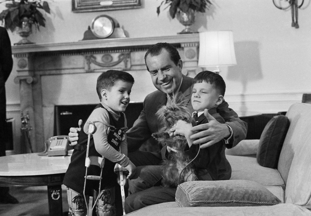 In this Feb. 5, 1969, file photo President Richard Nixon smiles as he shows off one of the White House pets tiny Yorkshire terrier Pasha to two junior visitors in his office in Washington. His guests are five-year-old Tracy Greenwood, the March of Dimes National Poster Child, and his 7-year-old brother Jamie. The arrival of the Biden pets will also mark the next chapter in a long history of pets residing at the White House after a four-year hiatus during the Trump administration. “Pets have always played an important role in the White House throughout the decades,” said Jennifer Pickens, an author who studies White House traditions. (AP Photo, File)